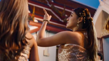 Geleneksel giyinmiş bir kadın Budist tapınağının süs çatısını göstererek Lois Krathong 'u kutluyor.