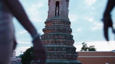 Bangkok 'ta Wat Arun Ratchawararam' da el ele tutuşan geleneksel Tayland kıyafetli iki genç kadın.