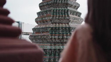 Geleneksel kıyafetler giyen iki Taylandlı kadın Bangkok 'taki Wat Arun tapınağında gülümsüyor ve konuşuyorlar.