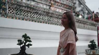 Geleneksel güzel elbiseli zarif Taylandlı kadın Wat Arun 'da başka bir insanla el ele tutuşuyor.