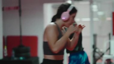 Genç kadınlar dövüş sporları eğitiminde, tekmeler ve gölge boksu teknikleri üzerinde çalışıyorlar.