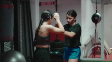 Profesyonel bayan eğitmen dövüş sporları salonunda genç bir öğrenciye Muay Thai teknikleri öğretiyor.