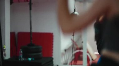 Kulaklık takan odaklanmış kadın dövüşçü tek başına spor salonunda gölge boks teknikleri uyguluyor.