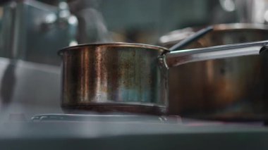 Paslanmaz çelik tencere. Mutfaktaki büyük, sıcak bir ocakta kaynayıp buharlaşıyor. 4K yatay.