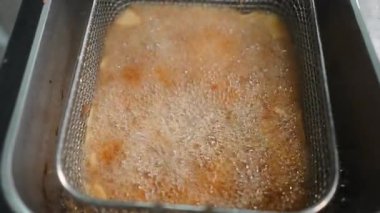 Patates kızartmasını kes ve sıcak yağda kızart. Bir kızartma sepeti içinde - 4K yatay.