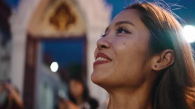 Genç Asyalı bir kadın geleneksel Tayland festivalinde gece mutlu mesut bakıp gülümsüyor.
