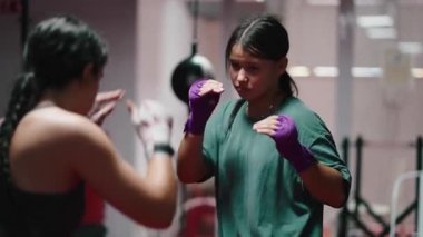 İki kararlı genç kadın antrenman sırasında boks teknikleri uyguluyor. 4K yatay.