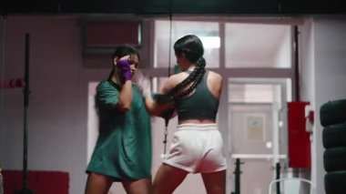 Spor salonunda boks, antrenman ve kavga yapan iki genç kadın. 4K yatay.
