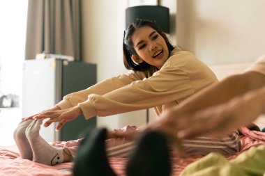 Genç bir kadın yatağa uzanıyor, ayaklarına uzanıyor. Evde sağlığın ve esnekliğin uygulanması.