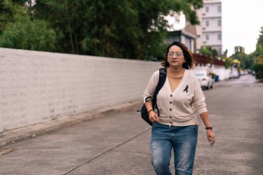 Dışarıda yürüyen bir kadın, siyah bir kurdele takıyor farkındalığı, desteği ya da yasını simgeliyor.