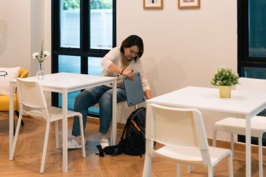 Kişisel eşyaları düzenleyen, bilgisayarları kapalı bir odada sırt çantasına koyan bir kadın.