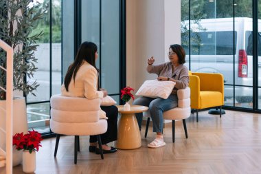 Kadınlar aktif olarak iletişim kuruyor, görüşlerini paylaşıyor ve rahat bir ofis ortamında dinleme yapıyorlar.