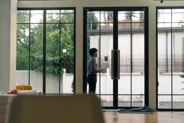 Davetkar ve modern bir evde ya da ofis kapısında elinde dijital tabletle duran kişi