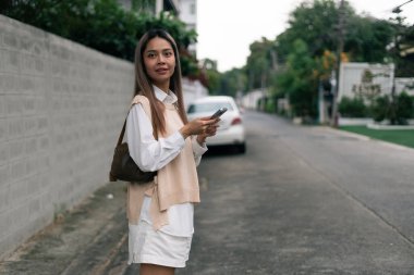 Akıllı telefondan mesajlaşan genç bir kadın, şehir ortamında güven ve bağlantıyla geziniyor.