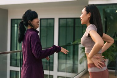 İki arkadaş modern bir balkonda aktif olarak sohbet ediyorlar, deneyimleri ve olumlu duyguları paylaşıyorlar.