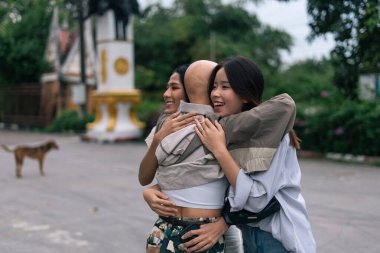 Neşeli Asyalı arkadaşlar sıcak bir kucaklaşmayı paylaşıyor, mutluluğu, arkadaşlığı ve dışarıdaki bağlantıyı ifade ediyorlar.