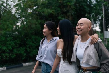 Genç Asyalı bayan arkadaşlar dışarıda yürüyüş yapıyor, neşe ve arkadaşlıklarını paylaşıyorlar.