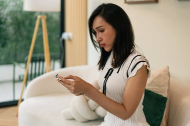 Kanepede oturan kadın, iletişim ve dijital etkileşim için cep telefonu kullanıyor.