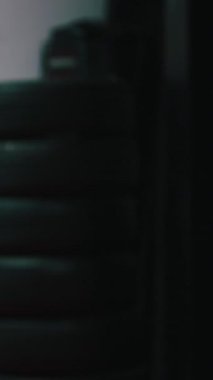 Kickboks antrenmanı yapan gençler karanlık bir spor salonunda ağır bir çuvala çakıyorlar.