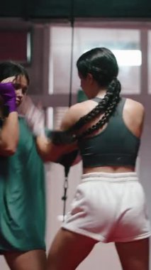 İki kadın ellerini sarmalayıp spor salonunda dövüş ve savunma becerilerini geliştiriyorlar.