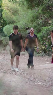 Doğadaki bir yaz macerası sırasında toprak yolda yürüyen aktif gençler - 4K Yatay