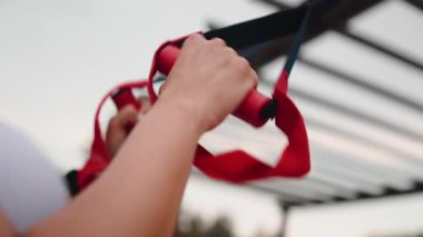 Atletik kadın elleri, açık hava jimnastik egzersizleri sırasında süspansiyon antrenörünü kavrıyor.