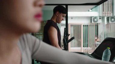 Genç erkek ve kadın arkadaşlar koşu bandında koşuyorlar modern bir spor salonunda, birlikte antrenman yapıyorlar.