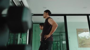 Sağlıklı Asyalı bir çift modern bir spor salonunda koşu bantları üzerinde kilo vermek için egzersiz yapıyor.