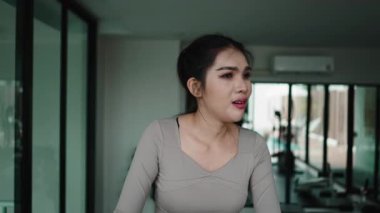 Genç Asyalı kadın spor salonunda nefes nefese ve yorgun hissediyordu.