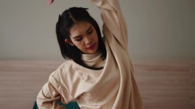 Genç Asyalı kadın evde rahatlamak için yoga yapıyor ve boynunu ve omuzlarını esnetiyor.