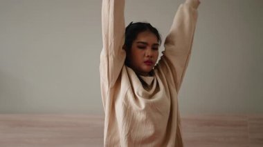 Atletik genç bayan odasında yerde otururken esneme egzersizleri yapıyor.