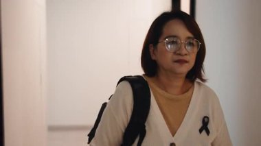 Siyah yas kurdeleli orta yaşlı bir iş kadını işten sonra apartman koridoruna giriyor.