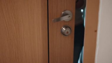 Sırt çantalı bir kadın eve geliyor, ön kapıyı açıyor, içeri giriyor ve kapıyı arkasından kapatıyor.