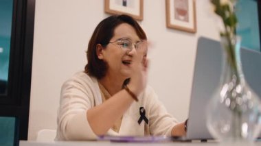 Gözlüklü orta yaşlı bir kadın ofisinde çalışırken video konferansı sırasında iletişim kuruyor.