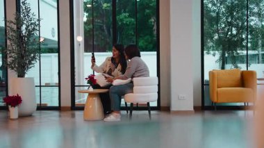 Modern bir kahve dükkanında cep telefonuyla selfie çeken iki neşeli genç kadın.