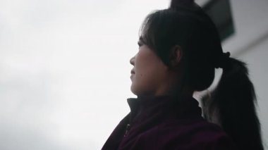 At kuyruklu genç Asyalı kadın yoga yaparken kolunu gökyüzüne doğru uzatıyor.