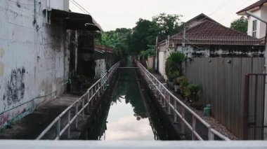 Genç bir çift, Asyalı bir köyde küçük bir su yolu üzerinde romantik bir yürüyüş yapıyor.