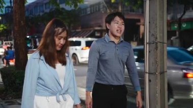 Genç Asyalı çift, meşgul bir şehir caddesinde yürürken sohbet ediyorlar.