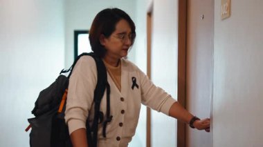 Sırt çantalı, ön kapısının kilidini açıp apartmanına giren olgun bir kadın.