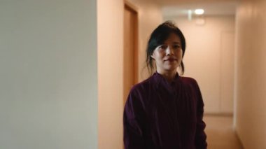 Güzel, orta yaşlı Asyalı kadın, parlak bir koridordan spor salonuna doğru güvenle yürüyor.