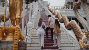 Bir grup genç turist Asya 'daki antik bir Budist tapınağının uzun merdivenlerinde yürüyorlar.