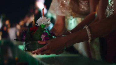 Geleneksel Tayland elbisesi giymiş iki genç kadın, bir Krathong 'u yüzdürerek Loi Krathong festivalini kutluyor.