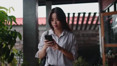 Genç Asyalı kadın video kaydediyor ya da güzel bir terasta cep telefonuyla fotoğraf çekiyor - 4K yatay