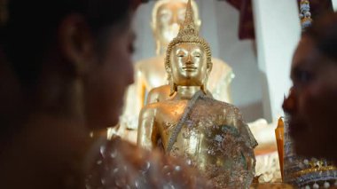 Bangkok 'taki Loi Krathong festivali sırasında Wat Arun' da bir Buda heykeline dua eden iki genç Asyalı kadın.