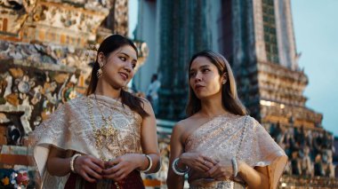 Geleneksel kıyafet ve mücevherlerle iki Taylandlı kadın Wat Arun Tapınağı 'nda Lou Krathong festivalini kutluyor.