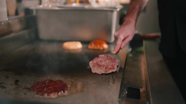 Erkek aşçı sıcak bir restoranda köfte pişiriyor ve köfte pişiriyor.