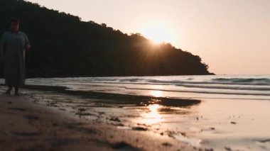 Altın güneş, Pattaya, Tayland 'da tropikal bir sahilde siluetli bir tepenin ardında batıyor.