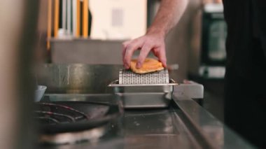 Erkek şeflerin elleri, ticari bir mutfakta paslanmaz çelikten bir tezgahın üzerinde brioche çörekleri rendeliyor.