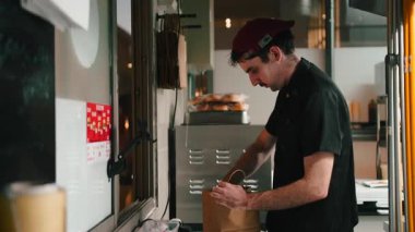 Restoran çalışanı paket servis siparişi için kese kağıdına yemek dolduruyor.