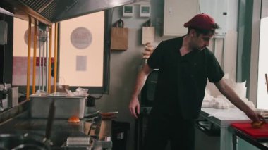 Erkek aşçı, bir fast food mutfağında gurme burger hazırlıyor ve birleştiriyor.